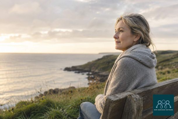 Person sitting peacefully by the coast reflecting, representing grief and the process of healing