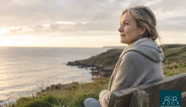 Person sitting peacefully by the coast reflecting, representing grief and the process of healing